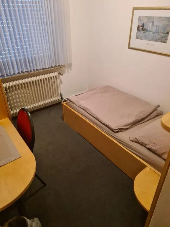 Komfortables Zimmer mit Bett und Tisch im Parkhotel Alex