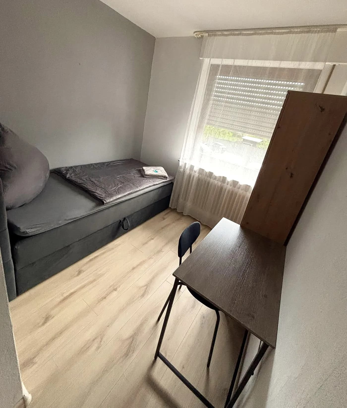 Renoviertes Einzelzimmer mit Boxspringbett, Schreibtisch und Fenster